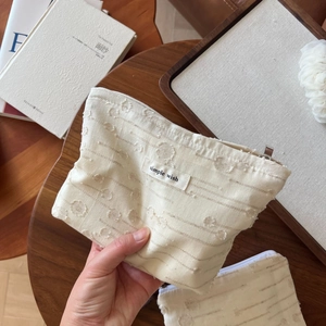 Detailed shot of cream linen makeup bag featuring 3D dot embroidery and zipper