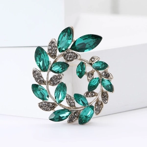 Close-up of olive branch crystal brooch with marquise-cut green stones and silver finish