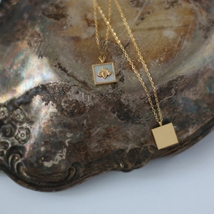 Detailed macro of gold bee pendant with white mother of pearl inlay on vintage tray