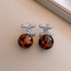 Close-up of leopard print resin beads and sparkling rhinestone geometric stud earrings