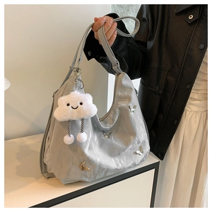 Close-up of silver oversized shoulder bag with metallic butterfly charms and plush cloud toy