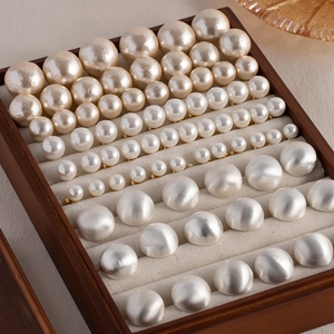 Macro shot of matte and glossy round bead stud earrings in a wooden jewelry box