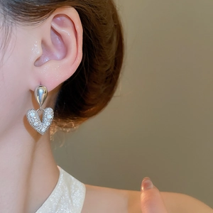 Boucles d'oreilles cœur en argent avec zircons étincelants portées par un mannequin