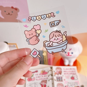 Detail of transparent cartoon stickers featuring a girl and bear for journaling