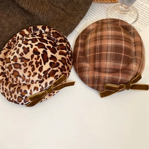 Leopard print and coffee plaid beret hats with velvet bows on warm knit background