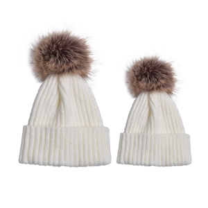 Dettaglio di cappelli genitore-figlio in maglia a coste bianche con pompon di pelliccia