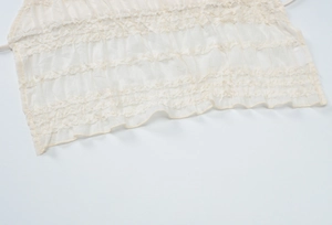 Détail du tissu beige de la robe dos nu montrant des plis horizontaux et des volants