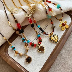 Vintage tiger eye bow and heart beaded necklaces displayed on a rustic wooden tray