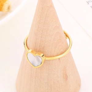 Golden stainless steel heart ring with white inlay on a wooden display stand