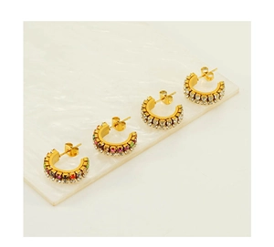Vue détaillée de boucles d'oreilles créoles dorées en C avec double rangée de strass