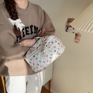 Detail of quilted cosmetic bag with cute bear prints and floral patterns in hand