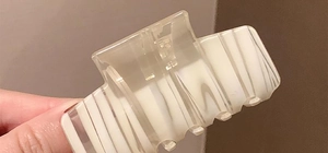 Detail of a rectangular translucent hair claw clip with white vertical stripes finish
