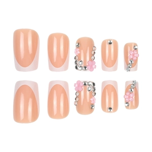 Faux ongles French roses avec fleurs 3D et strass sur fond blanc pour manucure douce