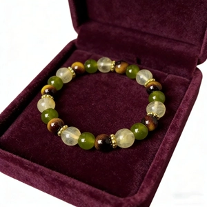 Detailed macro shot of beaded stretch bracelet with green and tiger eye stones in a velvet box