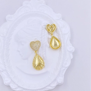 Detailed view of gold heart and teardrop earrings with sunburst pattern and cubic zirconia