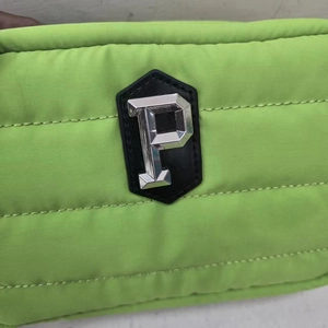 Close-up of bright green quilted crossbody bag with silver metallic letter P logo