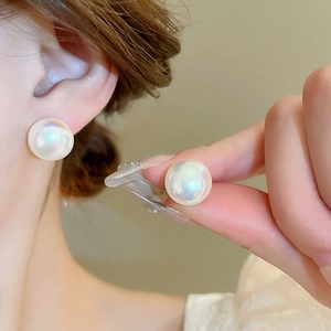 Detailed view of large mermaid pearl studs with iridescent glow and gold plating
