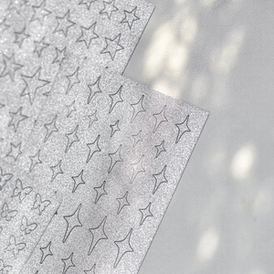 Macro detail of silver glitter nail stickers in star and butterfly shapes for art
