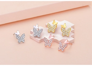 Detail of butterfly earrings in silver, gold, and rose gold with zircon inlay