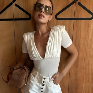 Sultry white V-neck bodysuit with ruching detail, paired with a brown suede handbag