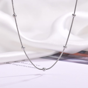 Macro shot of silver snake chain necklace featuring five polished stainless steel beads