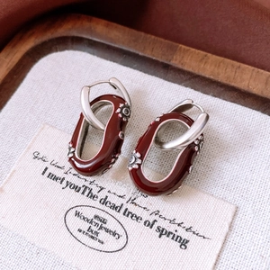 Détail macro de boucles d'oreilles vintage bordeaux avec relief fleuri sur lin fin