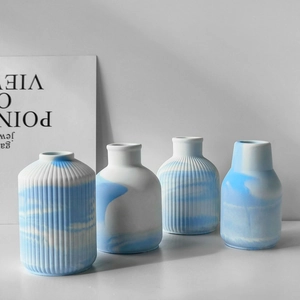 Set of four minimalist white and blue marble patterned ceramic vases with ribbed texture