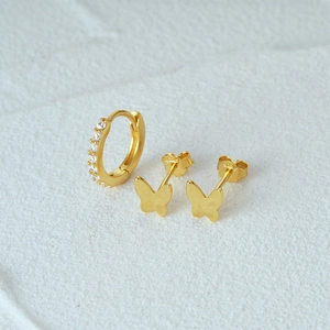 Close-up of gold butterfly earrings and a small diamond-encrusted hoop earring set