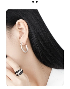 Close-up of S925 sterling silver geometric earrings and black-white textured ring on model