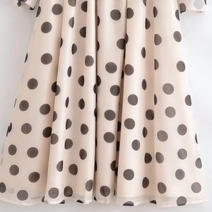 Détail du tissu en mousseline beige léger avec des pois gris élégants sur la jupe