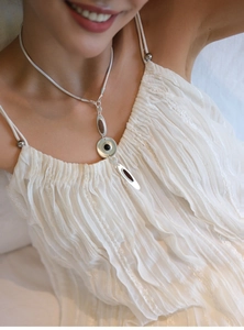 Silver-tone geometric Y-necklace with black drip oil pendants on a white dress