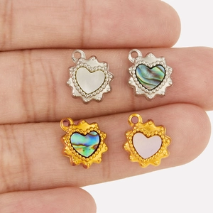 Detail view of heart shaped pendants with white shell and abalone inlay on fingers