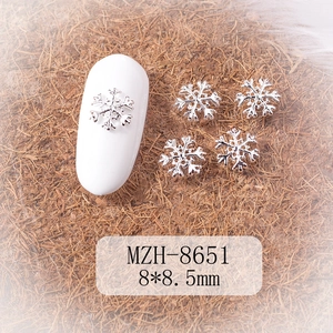 Macro shot of silver 8.5mm snowflake nail charms with dimension labels for DIY manicures