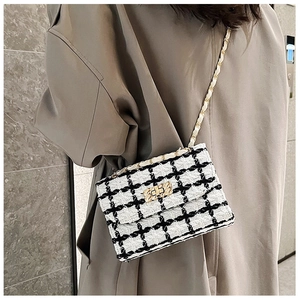Detail of tweed crossbody bag with gold chain strap and textured woven lock on model