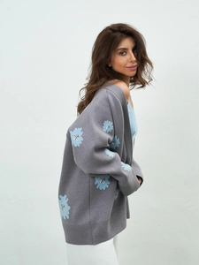 Detail view of grey knit cardigan featuring blue flower embroidery and loose drape fit