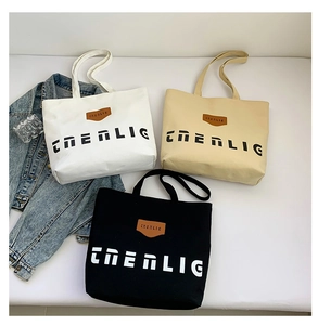 Detailed arrangement of large canvas tote bags in white, beige, and black with brand logo