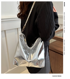 Detail of silver metallic hobo bag with woven chain strap worn by a model