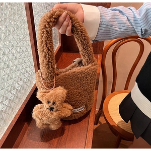 Détail du sac seau en peluche marron avec pendentif ours et étiquette CLEAR K tissée