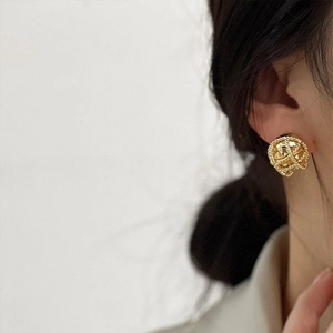 Detail of vintage gold-tone woven ball stud earrings with intricate metallic texture