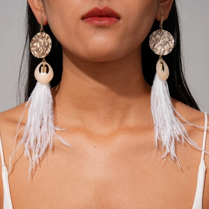 Detail of bohemian long earrings with white feathers and golden textured discs on model