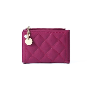 Detail of purple quilted wallet featuring lychee texture and pearl gold charm pendant
