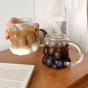 Detail einer Glas-Tasse mit Blasen-Textur, Latte Kaffee in der Hand gehalten
