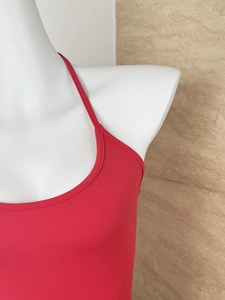 Detail of red backless cropped tank top with soft texture and slim fit design on white mannequin