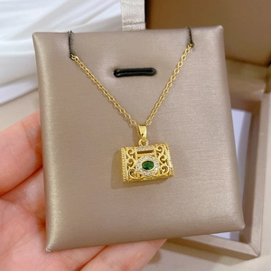 Detail of vintage gold-plated necklace with green gemstone and intricate cut-outs