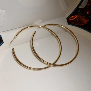Close-up of golden hoop earrings with a polished finish inside a white jewelry box