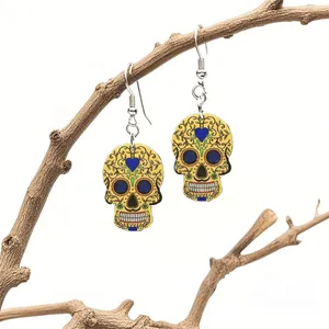 Detail of yellow acrylic sugar skull earrings with floral relief on a wooden branch