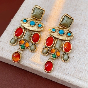 Close-up of vintage flower earrings with colorful beads and golden hammered metal texture