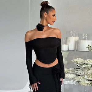 Close-up of black off-shoulder long sleeve top with textured knit and floral neck accessory