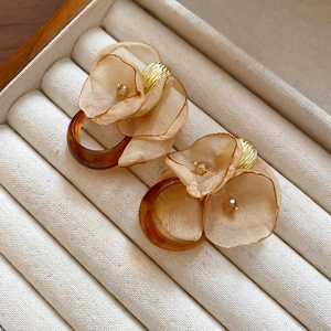 Macro detail of French retro chiffon flower earrings with amber resin and gold metal