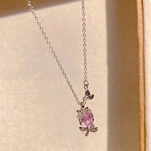 Close-up of silver tulip pendant necklace with pink zircon on woven texture background
